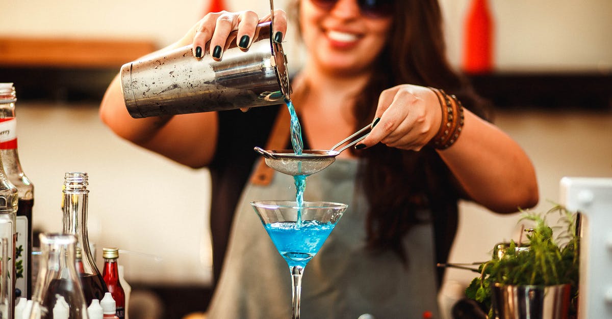 Shaking cocktails without bar equipment - Crop cheerful woman preparing homemade blue cocktail in bar