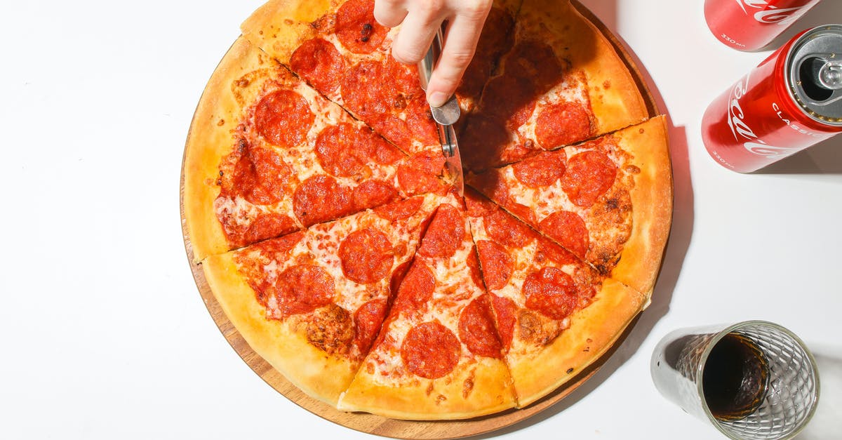 Shaping thick crust pizza dough - Person Slicing A Pizza With A Pizza Cutter