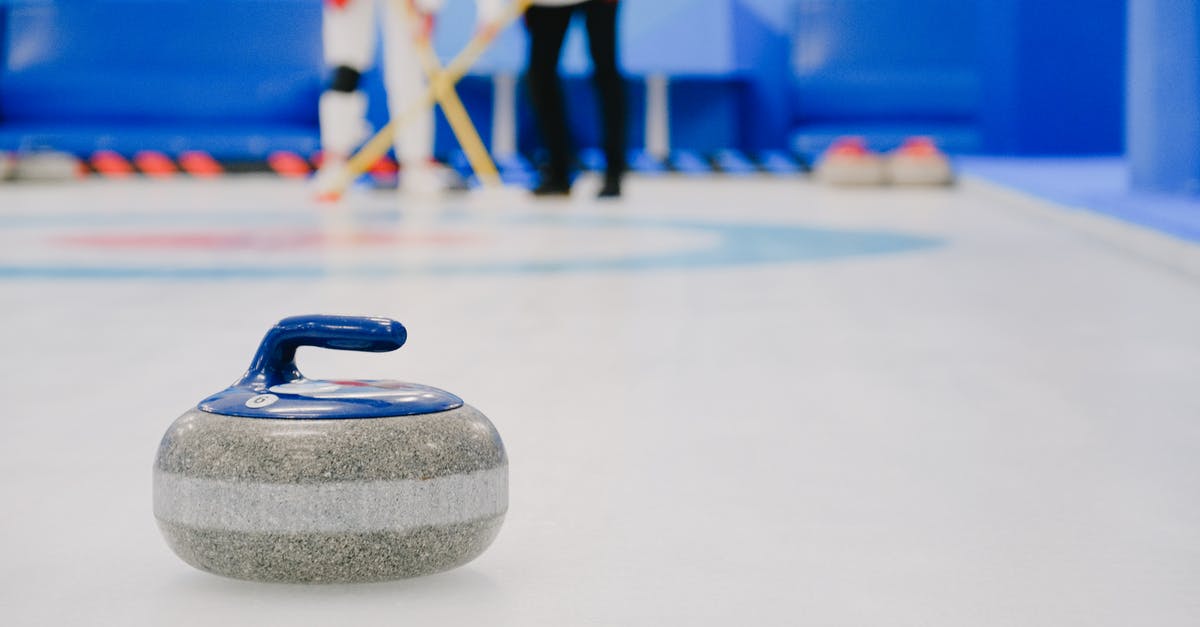 Shell-on Frozen Prawns and Power Outage - Curling stone placed on ice against sportsmen on ice rink