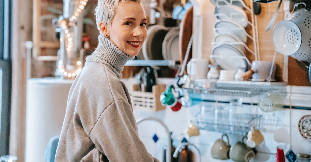 Short-term bread storage - Side view of adult sincere female with cup of hot drink looking at camera in house