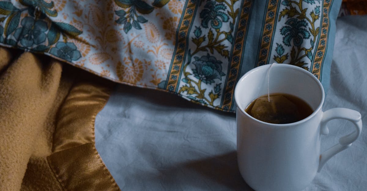Should a [Ceramic] mug be left covered or uncovered during the tea bag steeping process? - From above of white mug of hot drink placed on bed near blanket and pillow