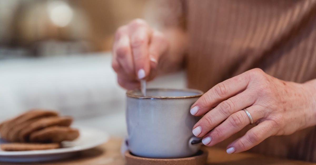 Should a [Ceramic] mug be left covered or uncovered during the tea bag steeping process? - Crop unrecognizable female preparing hot beverage in mug at desk with tasty biscuits in house