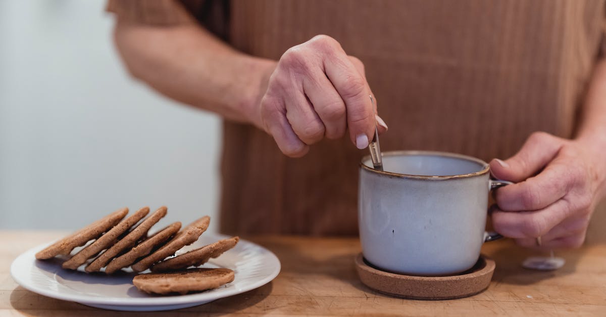 Should a [Ceramic] mug be left covered or uncovered during the tea bag steeping process? - Faceless woman stirring tea at table with delicious cookies