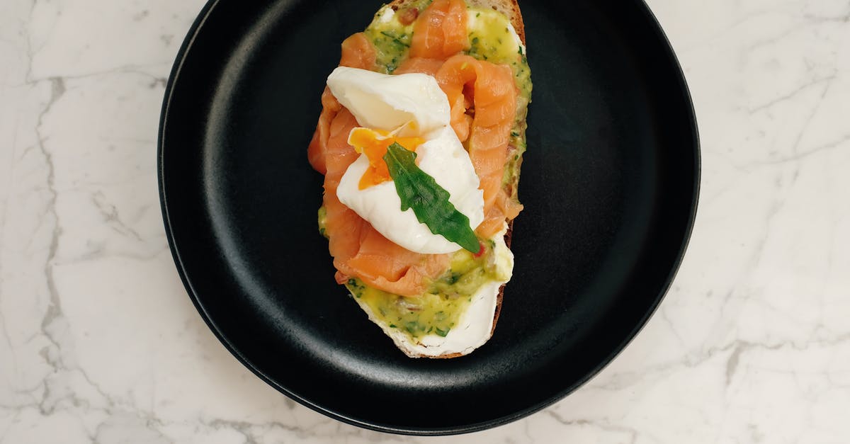 Should I cook frozen salmon differently from fresh salmon? - Top view of black ceramic plate with tasty toast with salmon and poached egg served on white marble table