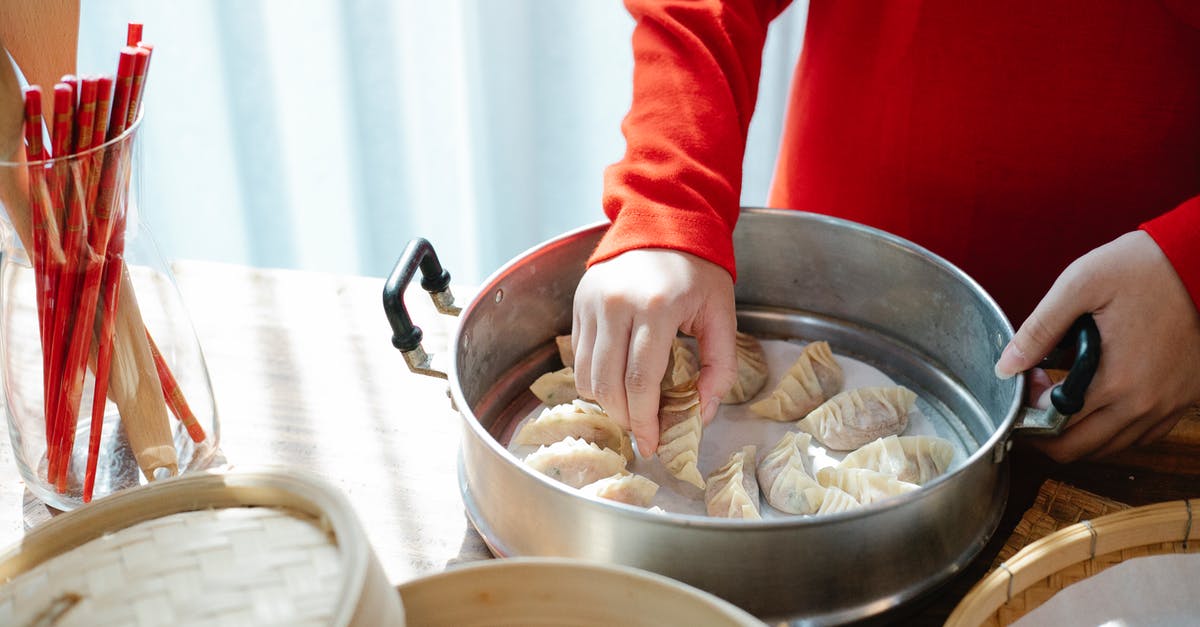 Should I freeze gyoza before or after cooking? - Person cooking gyoza dumplings in kitchen in daytime