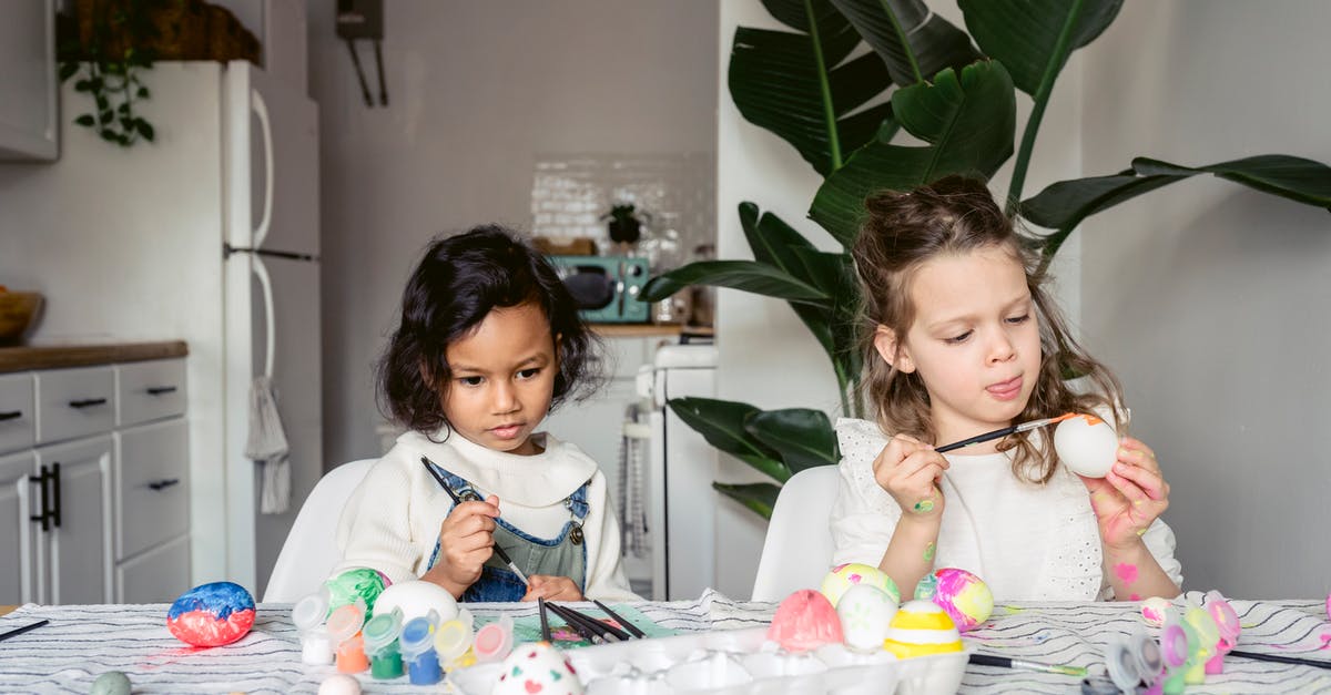 Should I refrigerate eggs? - Focused multiracial girls painting eggs in kitchen