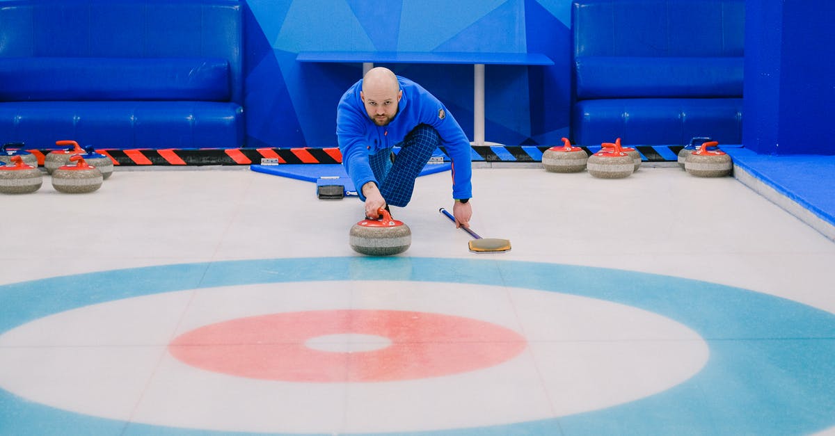 Should I throw moldy Strawberries away? - Focused male in blue activewear choosing tactic and throwing stone while playing curling on ice rink