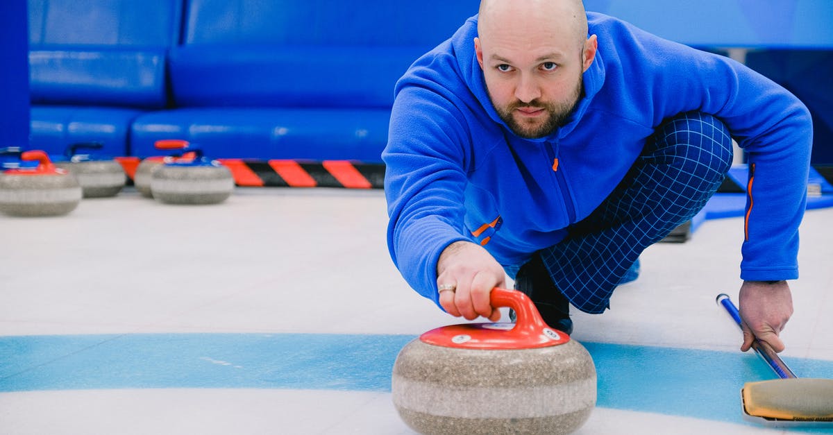 Should I throw moldy Strawberries away? - Concentrated sportsman in blue activewear squatting down and throwing heavy stone while playing curling on modern ice rink