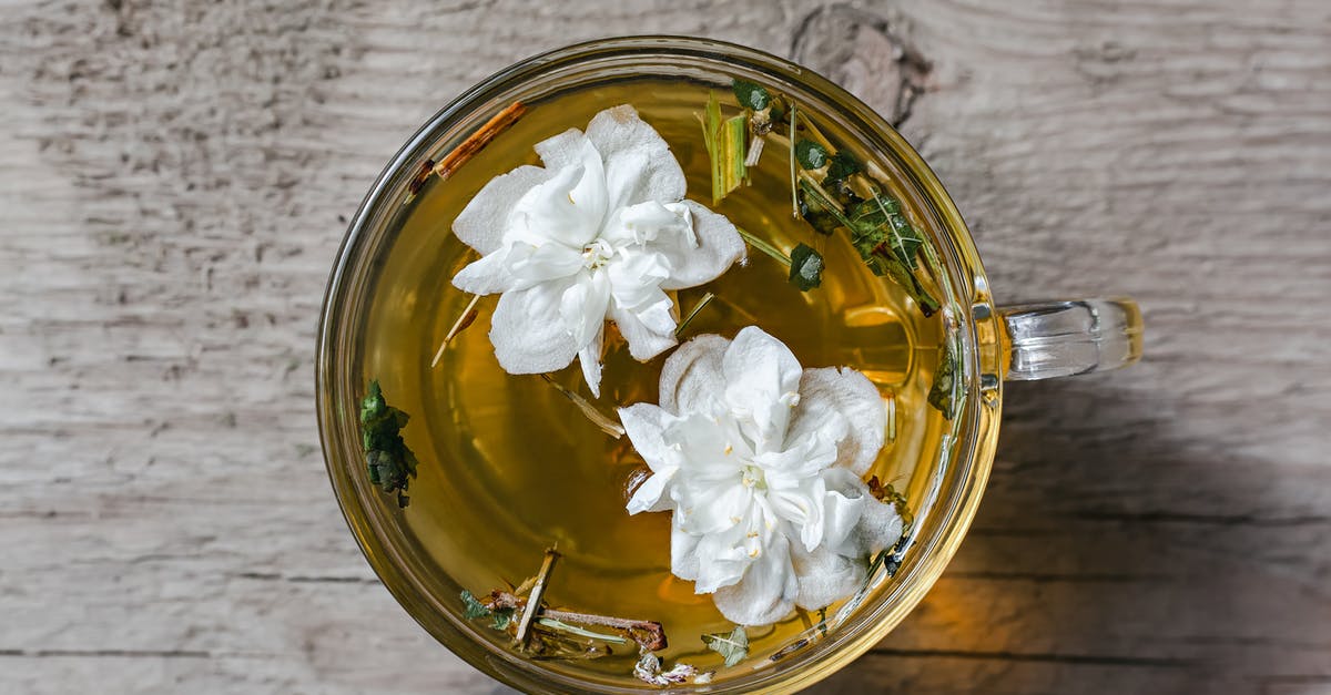 Should I use dried or fresh chilli/ginger in chai tea? - From above of aromatic herbal tea with fresh Arabian jasmine flowers in glass cup placed on wooden table in daylight