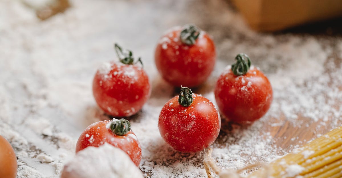 Should I use whole eggs or only yolks in Spaghetti alla Carbonara? - From above of ripe red cherry tomatoes with garlic and raw spaghetti on wooden table with flour