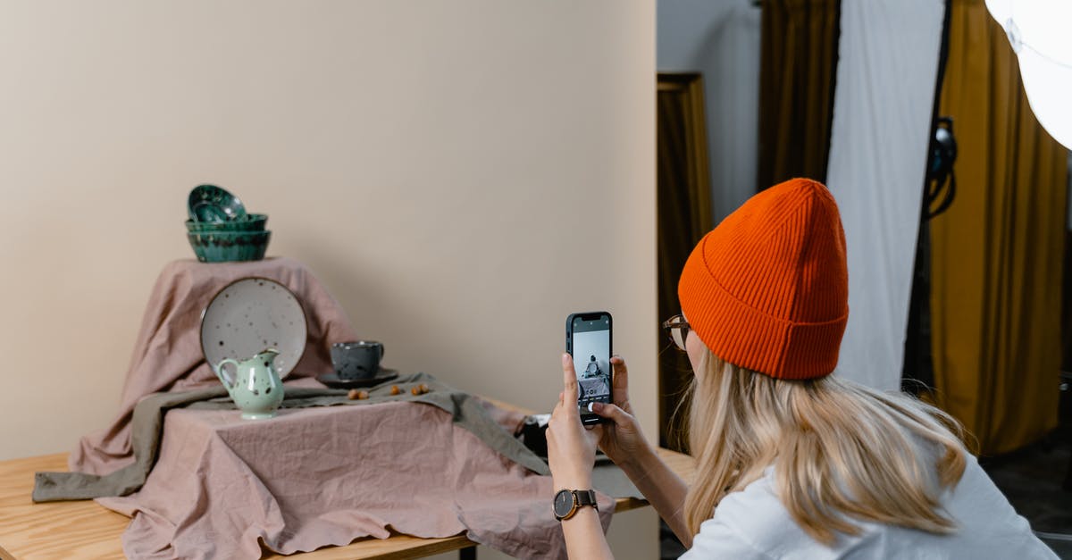 Should you store cutlery upside down? - Woman in White Shirt and Orange Knit Cap Holding a Smartphone