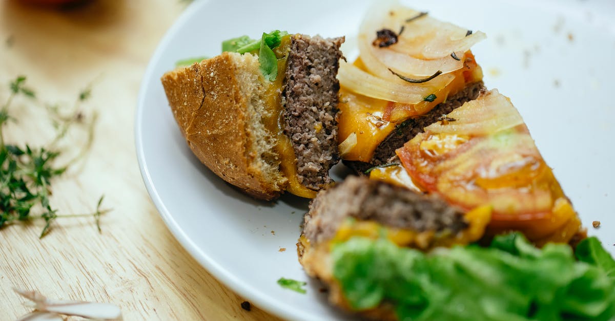 Silverside Beef Roast - tough to cut on the plate and chewy - Delicious burger with juicy cutlet lettuce an onions cut into quarters served on white plate and placed on wooden table in kitchen against blurred background