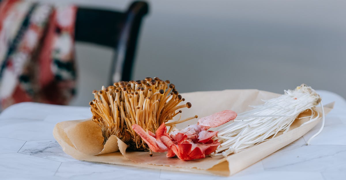 Simple recipe that when combined in a different order yields different food? - Little brown nameko mushrooms composed with pink oyster and enoki on paper package on blurred background