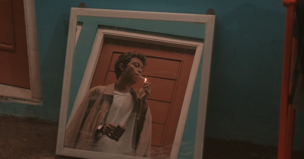 Smoke point and toxicity [closed] - Square mirror placed on floor in room and reflecting young rebellious Asian guy in stylish outfit smoking cigarette near door