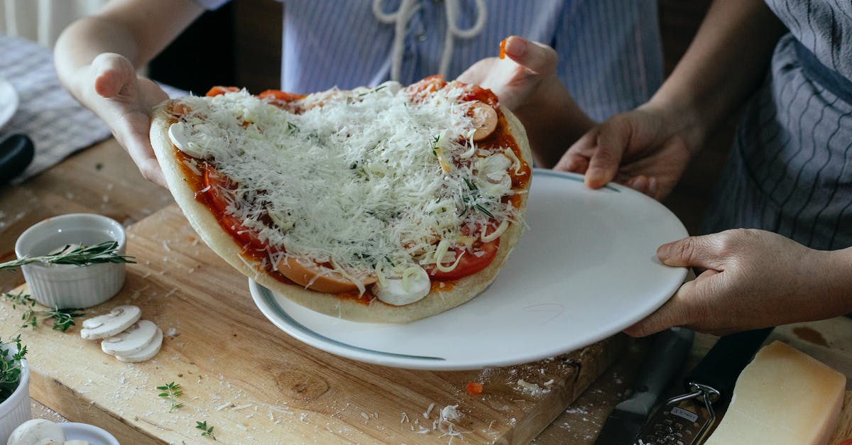 Something wrong with pizza dough - 3rd time in a row - High angle of crop anonymous women transferring uncooked yummy homemade pizza on platter during preparation to baking in kitchen