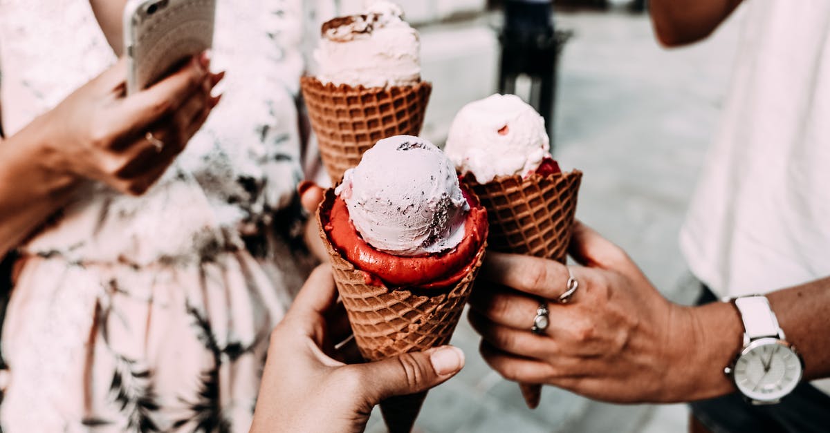 Sorbet tastes less sweet when frozen? - Crop anonymous friends in casual summer clothes clinking delicious cone ice creams while gathering on street