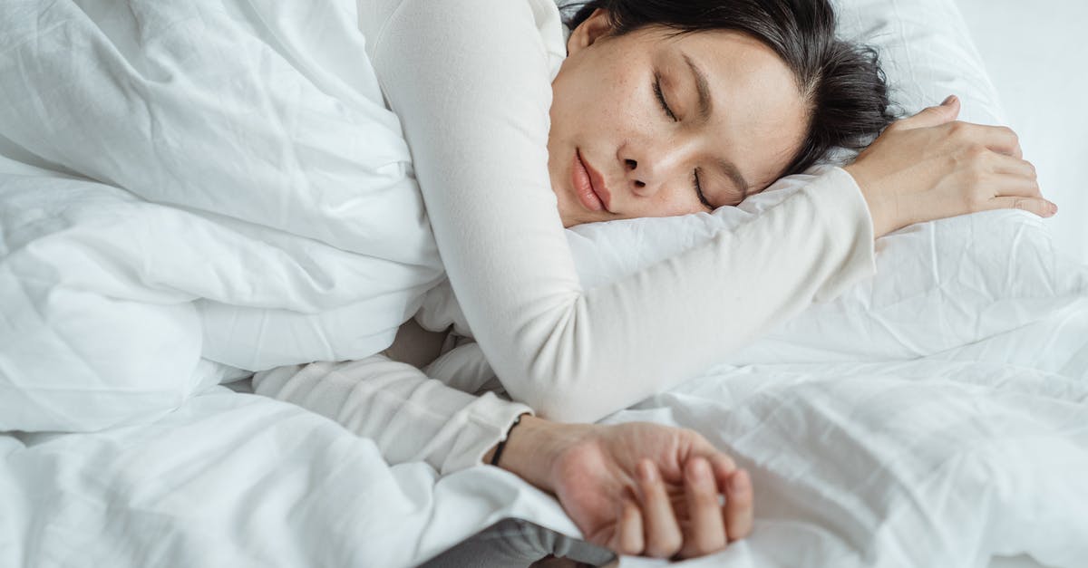 Sourdough starter used too early - Calm Asian female wearing white pajama sleeping in comfortable bed with white sheets near modern mobile phone in morning