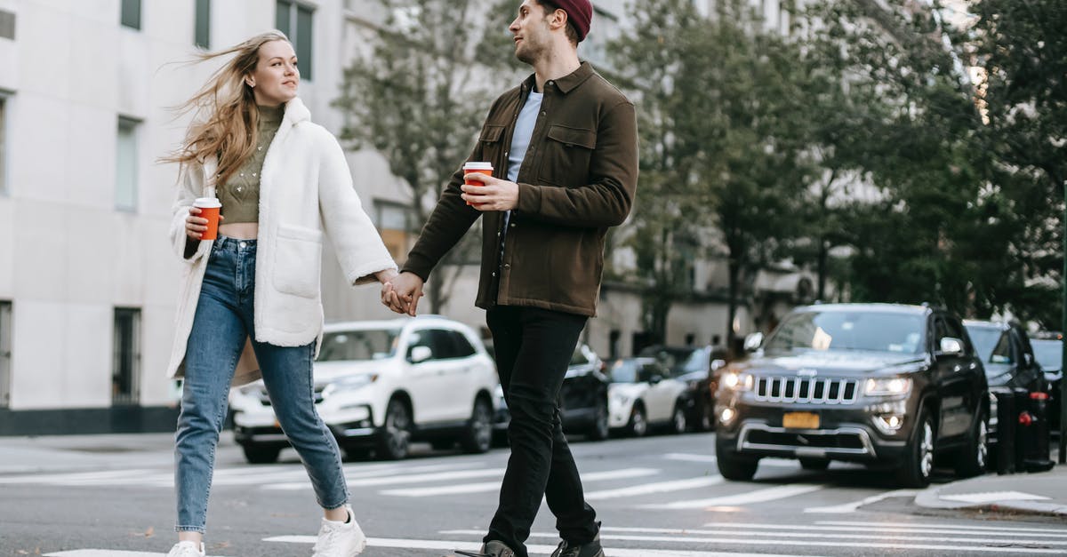 Sourdough teacakes/hot cross buns? - Young couple wearing warm jackets and with paper cups of hot drinks crossing road holding hands and looking at each other