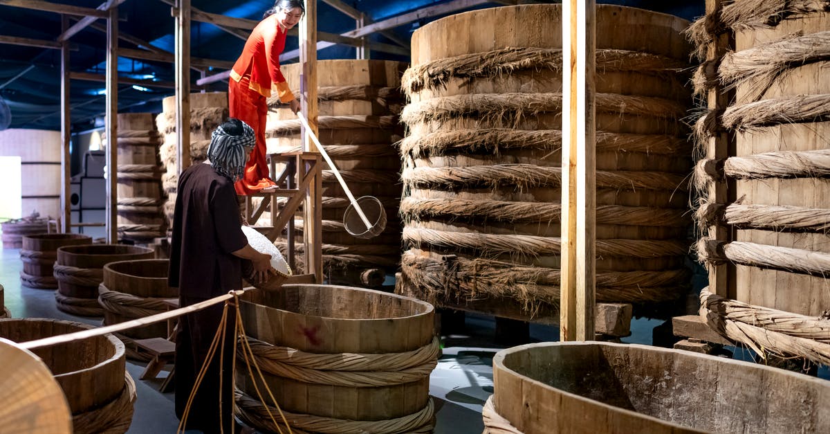 Soy Sauce storage container - Asian woman working with colleague in fish sauce factory