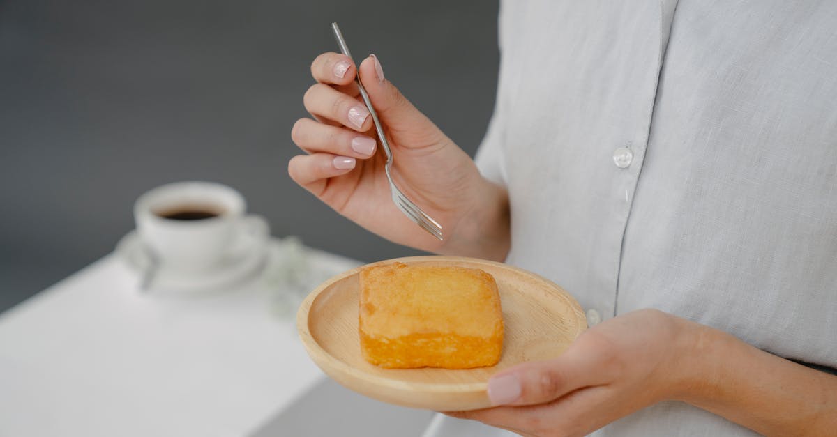 Sponge Cake vs (UK) Angel Cake: what's the difference - Soft focus of crop faceless female with tasty fresh butter cake on plate standing on gray background in studio with cup of coffee