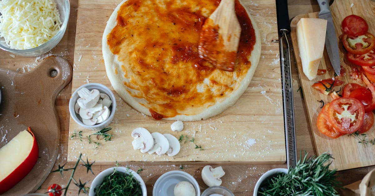 Stock Based Pizza Dough - Top view of fresh vegetables and cheese on wooden cutting boards on table during process of preparing pizza in kitchen