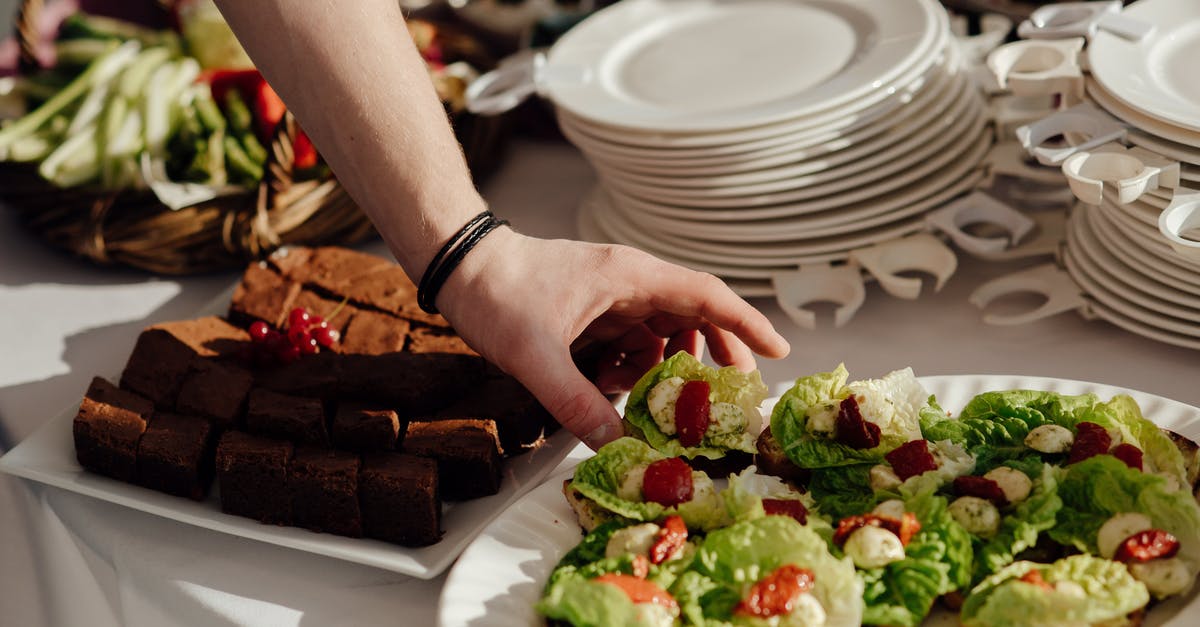 Storage of cheese starter cultures - Crop anonymous man taking snack with lettuce and cherry tomatoes with cheese from buffet table with brownie during banquet in restaurant