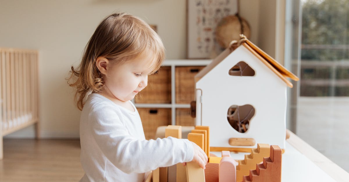 Storing knives: wood block or magnetic stripe? - Cute little girl playing with wooden blocks at table near window at home