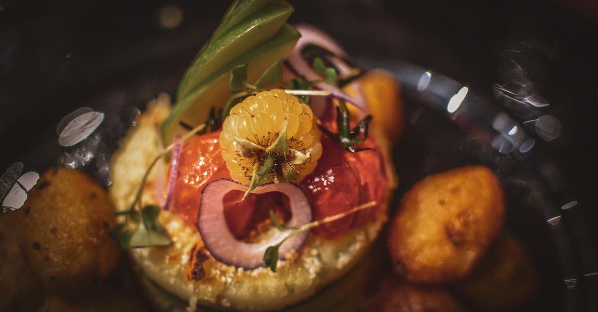 Storing unused portion of red onion - High angle of delicious yellow raspberry with sliced onions and avocado near sun dried tomatoes and green herbs on black background in dark room