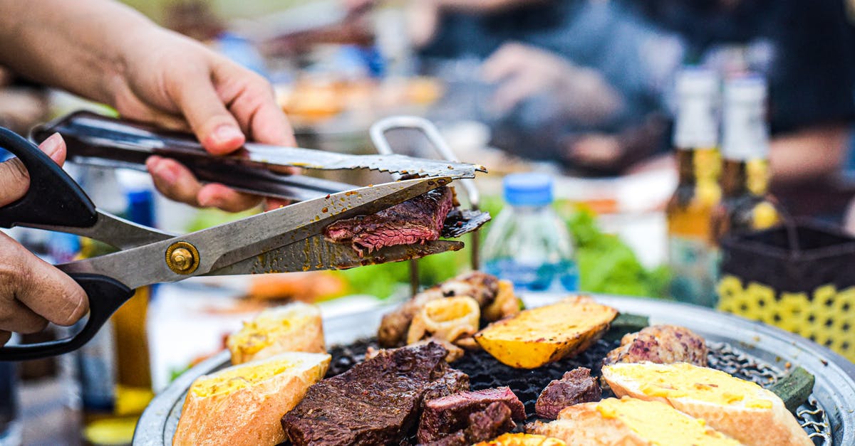 Stringy corned beef - Man Cutting Beef with Scissors Over a Barbecue