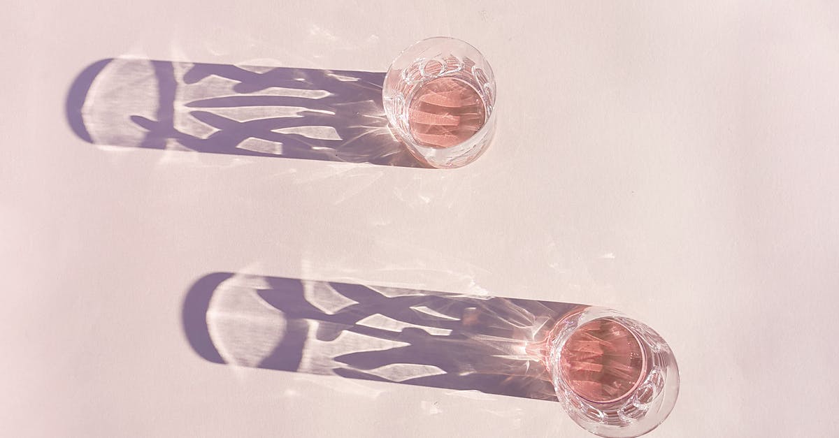 Stripping seasoning from cast iron - Top view of glass shots with pink wine placed on table and casting shades on sunny day