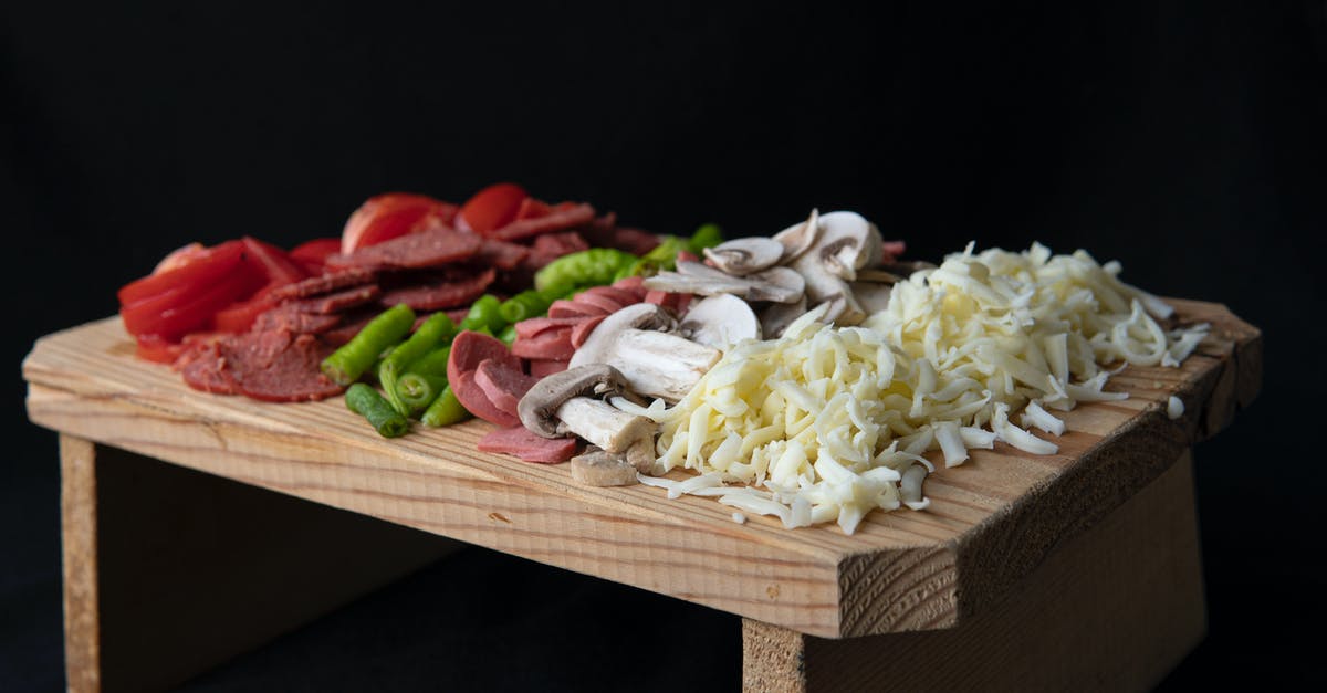 Substitute Cayenne Pepper for Black Pepper - Soft focus of sliced tomatoes and hot peppers placed on chopping board with sausages and grated cheese on black background