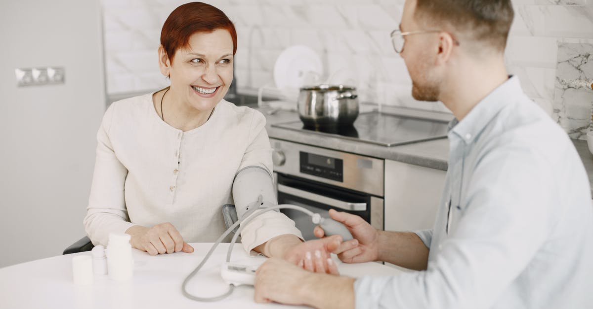 Substitute for blood? - A Man Sitting at a Table Checking a Woman's Blood Pressure