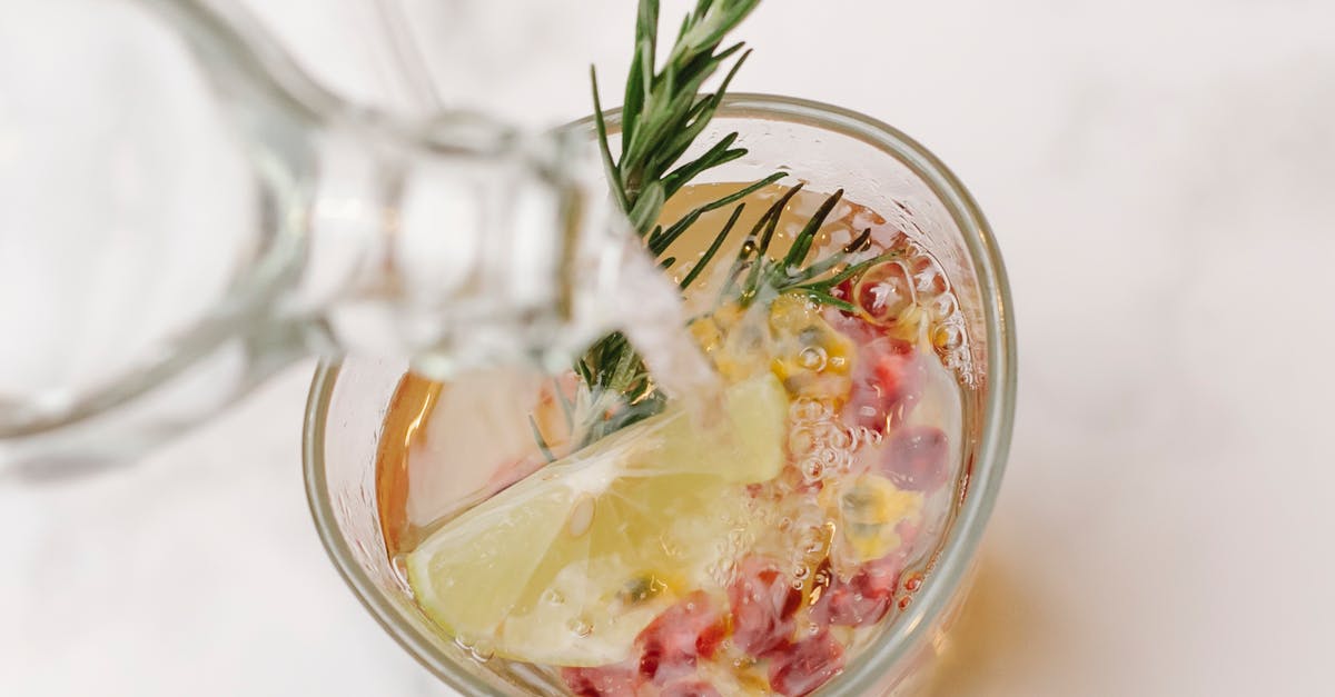 Substitute for fresh lemons - I need to make 70 liters of homemade lemonade - From above of glass bottle pouring water into glass with sprig of rosemary and slice of lemon placed on marble surface