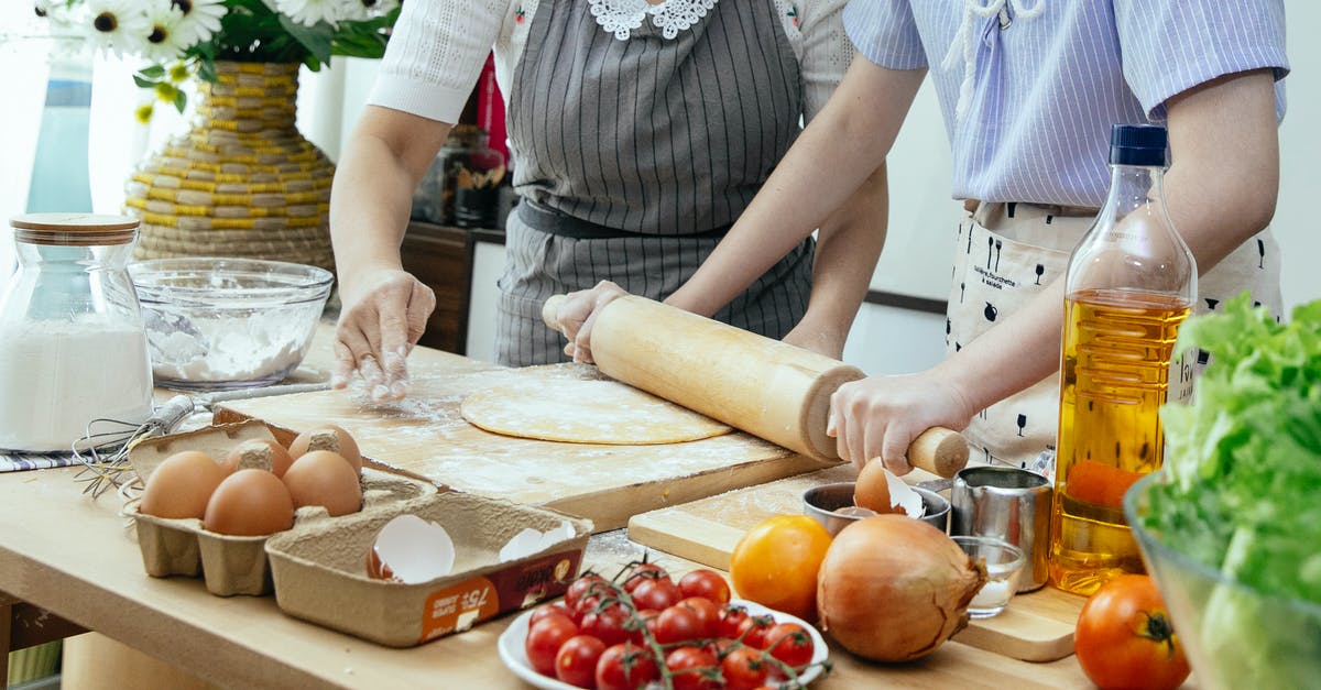 Substitute for Onion Powder - Unrecognizable female cooks rolling dough with pin on wooden board at table with various products while preparing pastry in kitchen