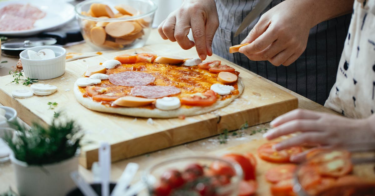 Substitutes for Italian sausage - Crop anonymous person in apron adding sausages on pizza with salami and champignons while cooking in kitchen