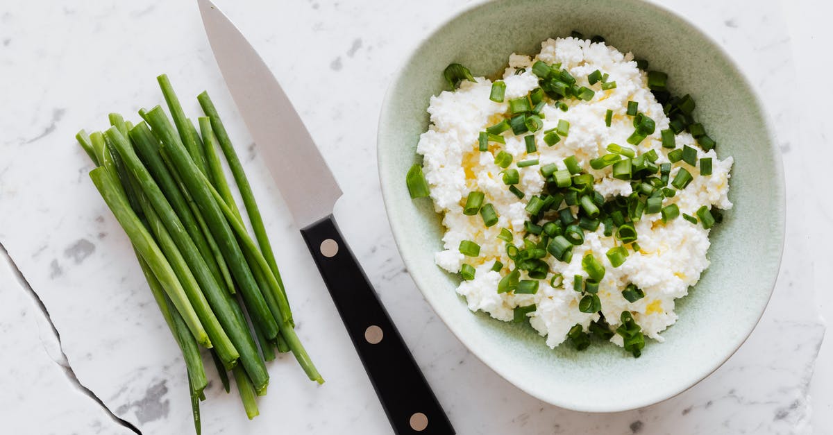 Substituting canola oil in salad - Top view of fresh salad with cottage cheese chopped onion oil and knife fresh greenery on white table with crack