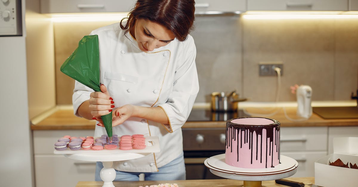 Substituting sugar with a liquid stevia concentrate in a cake - Female pastry chef adding cream on macaroons shells in modern bakery