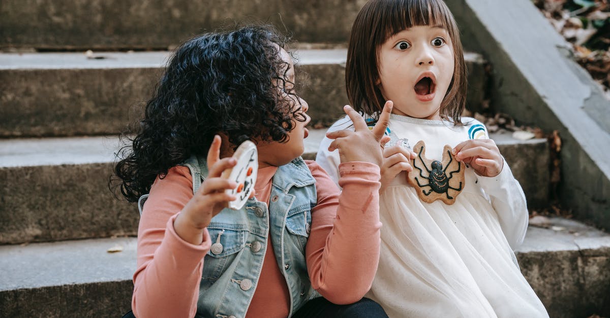 Sugar alternative when beating eggs and sugar together - Amazed diverse girls with Halloween gingerbread cookies sitting on staircase