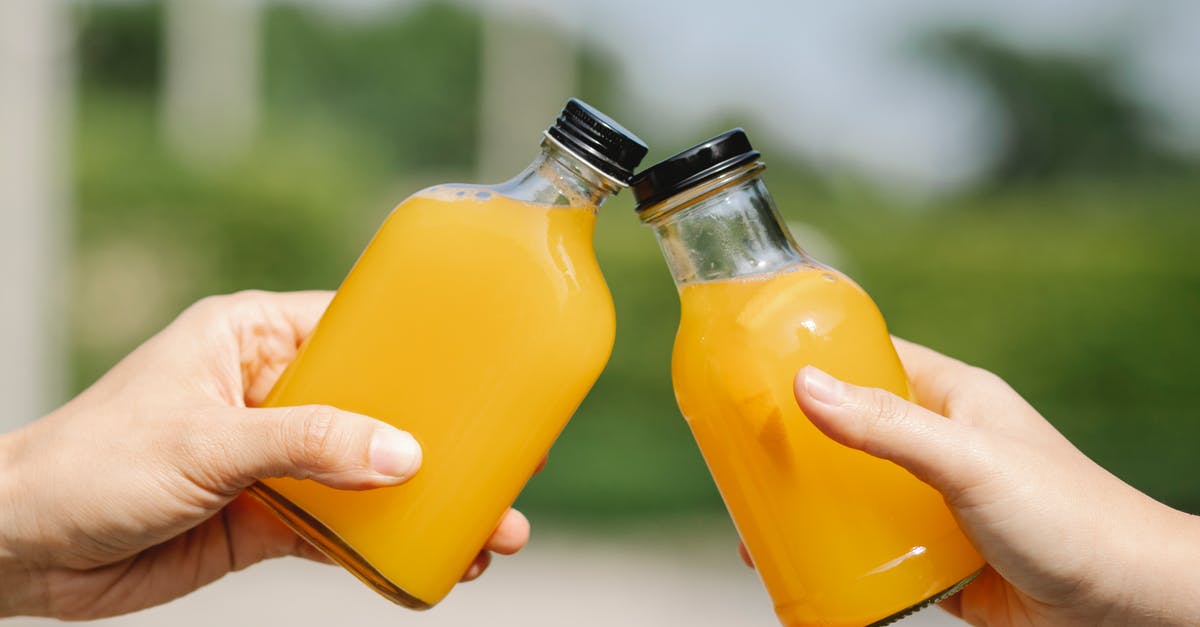 Sugar syrup with orange juice foams excessively - Crop person with bottles of orange juice