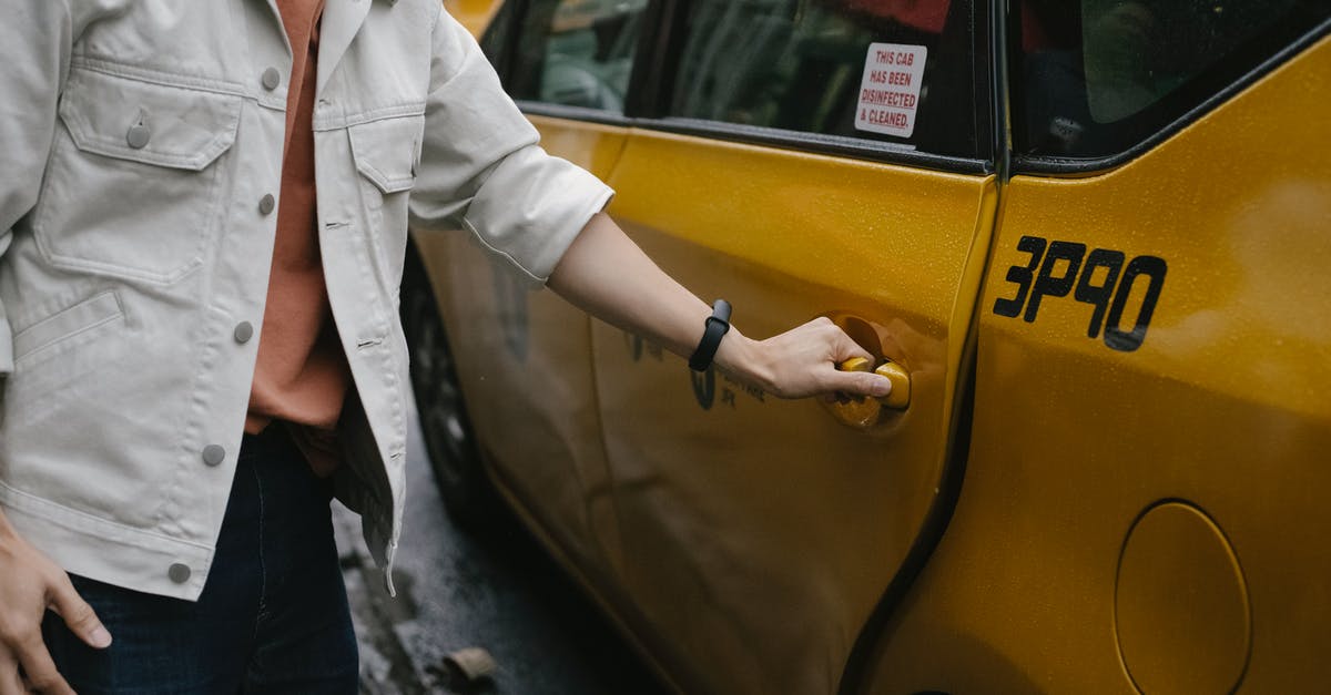 Suggestions for convenient and safe methods of transporting a few meals without a vehicle? - Unrecognizable passenger in casual clothes opening door of cab parked on roadside in city on street while commuting to work
