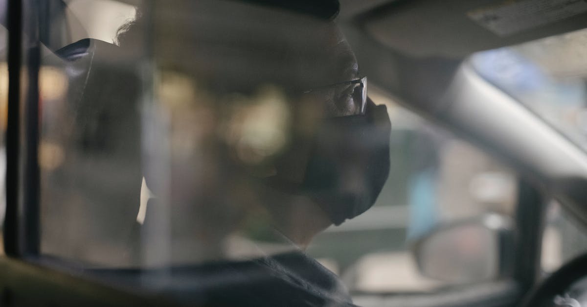 Suggestions for convenient and safe methods of transporting a few meals without a vehicle? - Through glass of crop concentrated ethnic man in eyeglasses sitting in car and wearing medical mask because of coronavirus pandemic