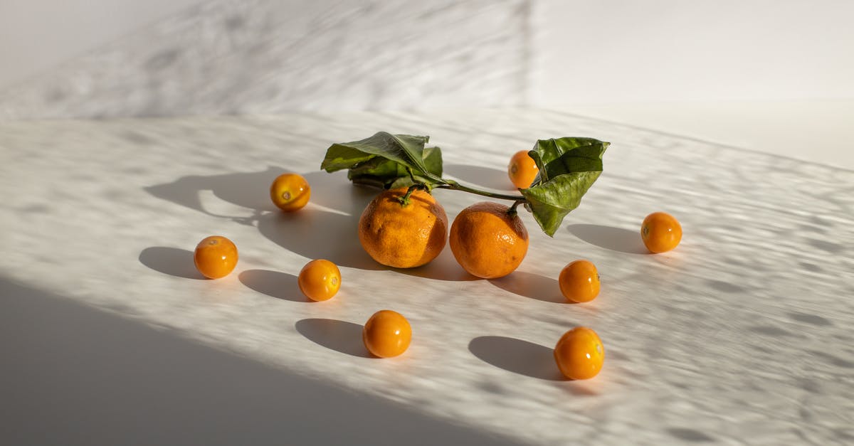 Sweet potatoes stored in direct sunlight - Healthy tangerines and groundcherries scattered on white surface in daylight