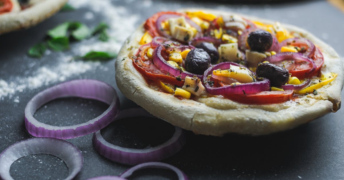 Tapioca flour pizza crust is gummy? - Cut pizza with olive and corn on thick dough served on table with flour