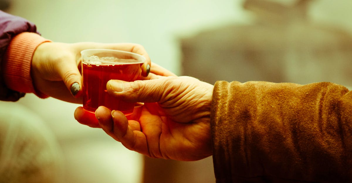 Tea cup residue - Person Holding Clear Drinking Glass With Brown Liquid