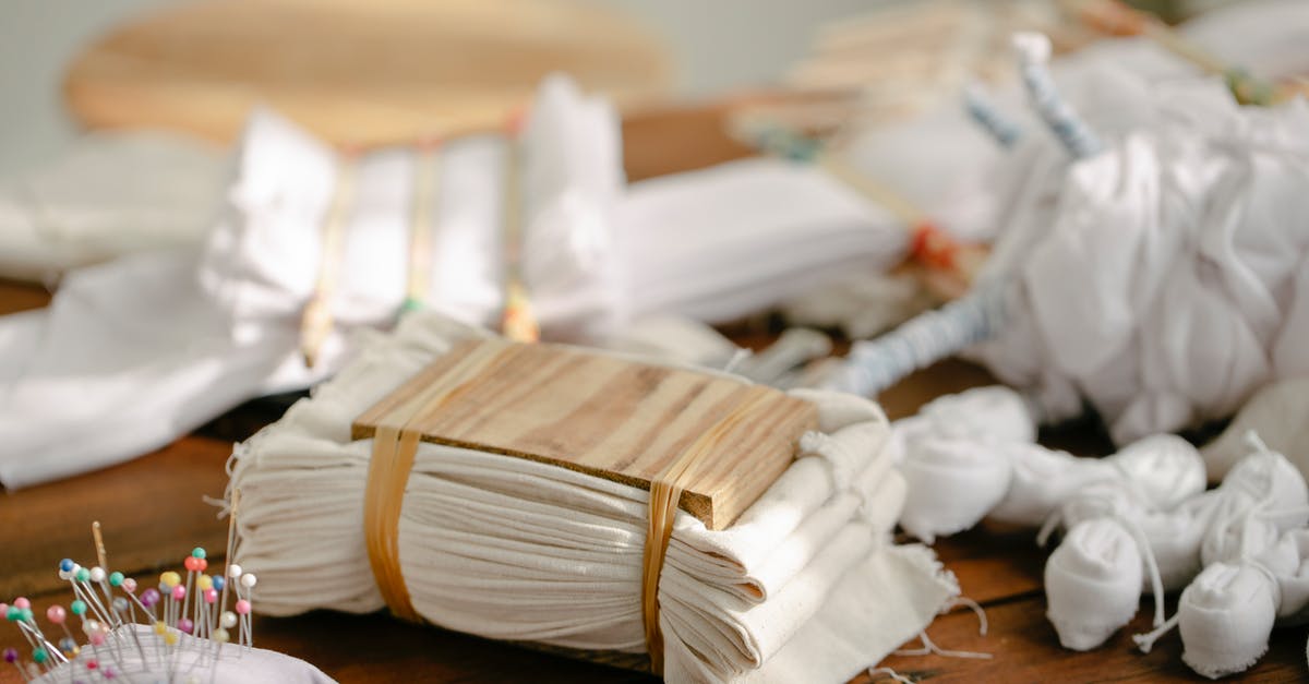 Technique to find and eliminate the needle bone in lamb shanks? - Abundance of tied fabric on table with various tools and equipment for shibori dyeing in light professional workshop on blurred background