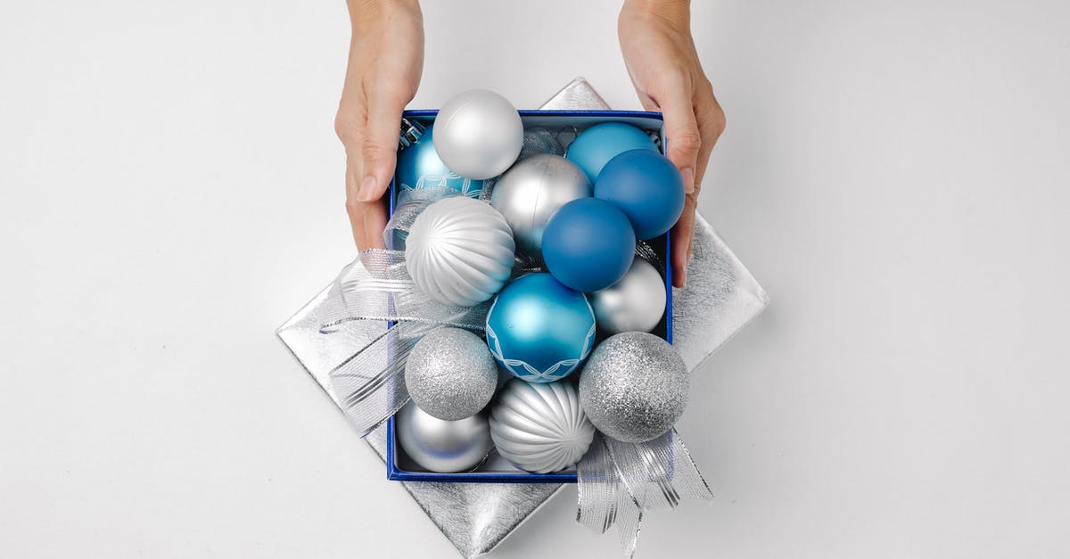 The inside of my grill lid is rusting - Top view of anonymous person with silver and blue Christmas balls on lid present of box placed on white background