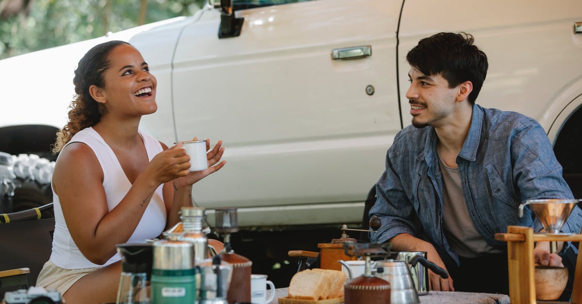 the whistle on the kettle keeps popping off - Positive multiethnic couple having lunch during picnic in nature