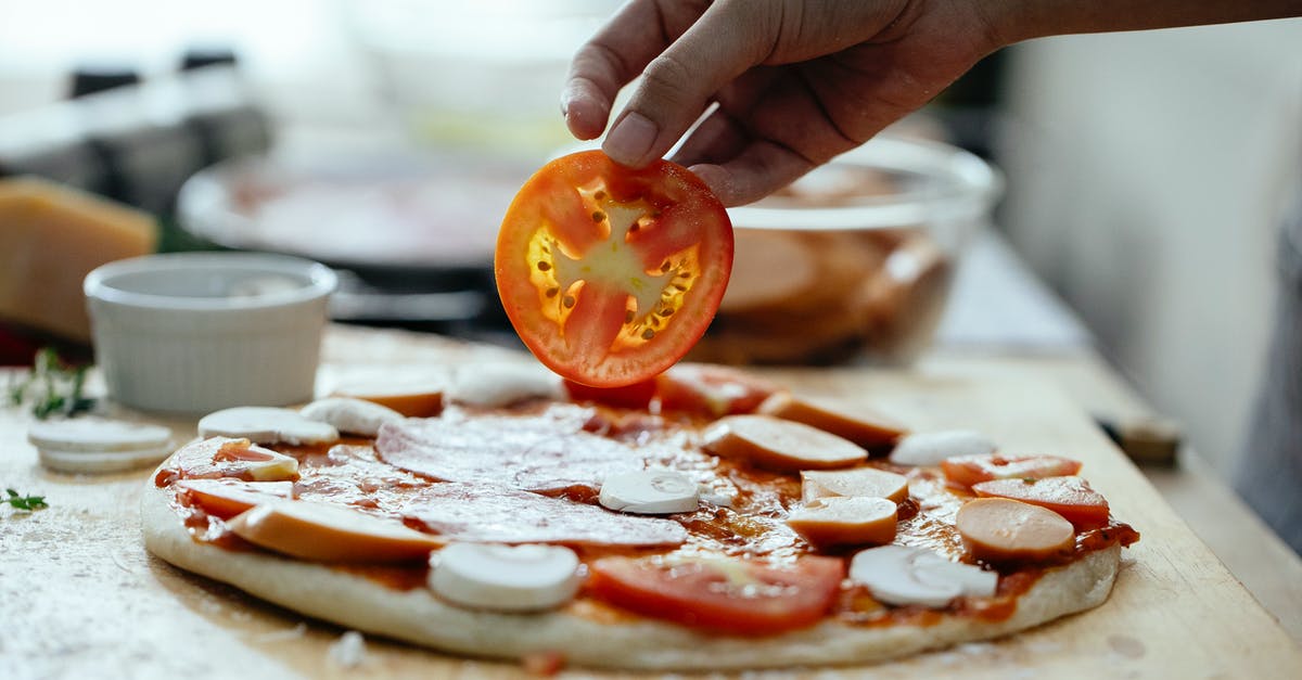 Thicker gelatin layer at the bottom of the dish - Unrecognizable person adding tomatoes in pizza