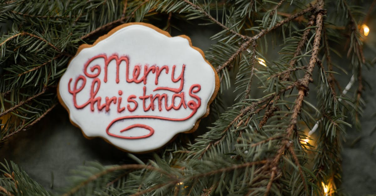 Thin chutney batch from a year ago - From above of yummy gingerbread cookie with inscription on sugar glaze between spruce sprigs with shiny garland during New Year holiday