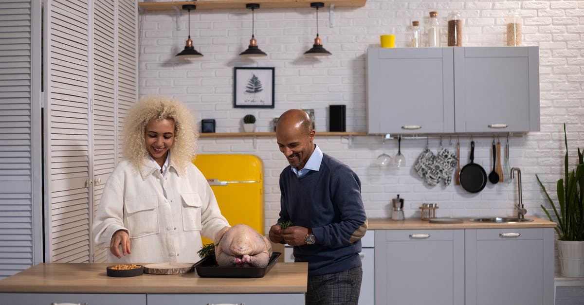 Thoroughly cooking stuffing in a Turkey - Positive black couple preparing turkey in kitchen
